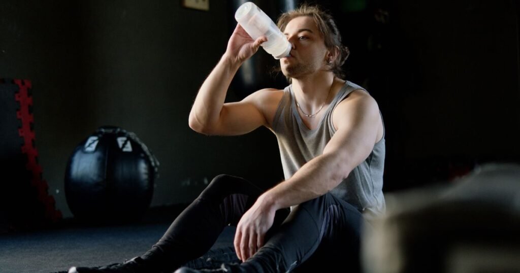 Athlete drinking from a large water bottle while executing bodybuilding peak week hydration protocols