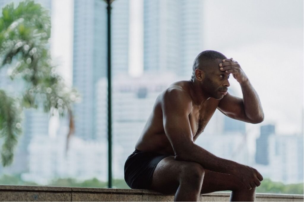 Stressed athlete holding his head outdoors, representing high cortisol levels and stress management for muscle recovery