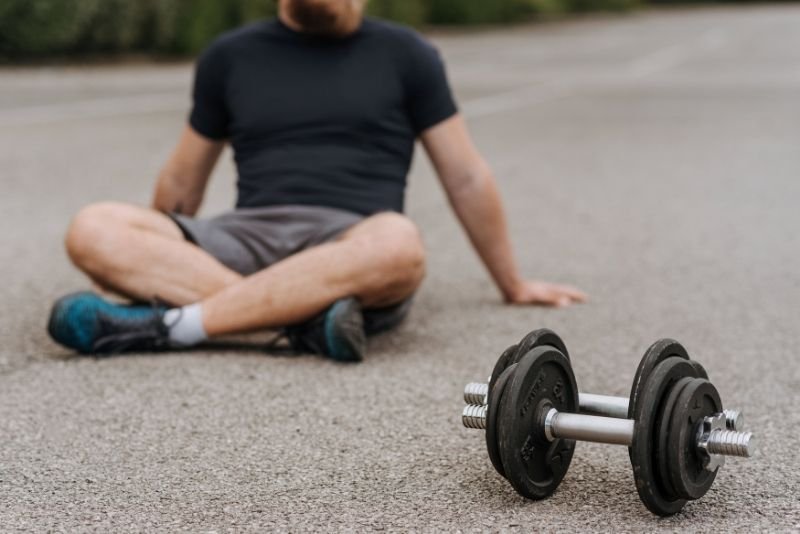Athlete resting behind an adjustable dumbbell after a heavy workout, needing muscle recovery in Chicago Illinois