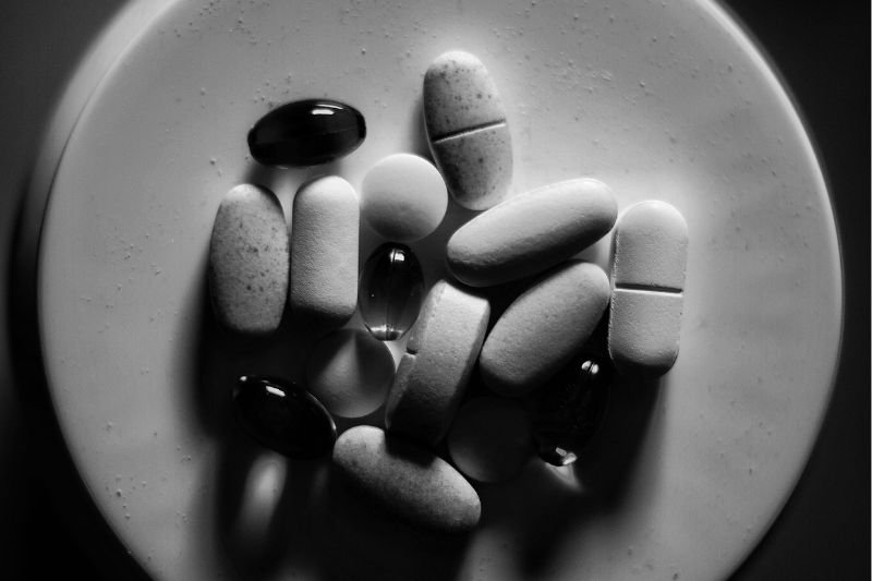 Black and white overhead view of various Pharmacore Laboratories LTD sports supplement pills and softgels