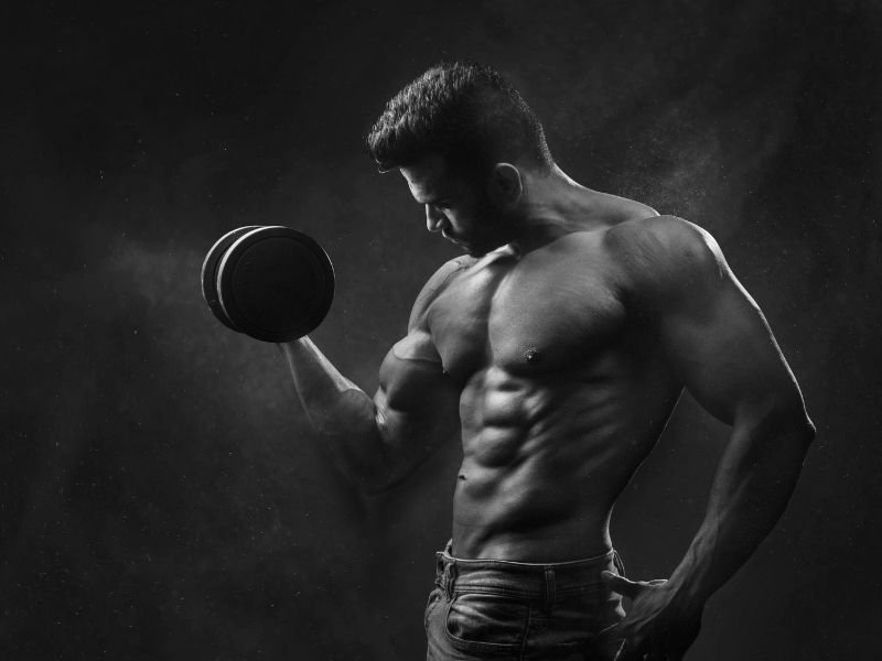 Muscular athlete performing strength training while researching Winstrol and stanozolol